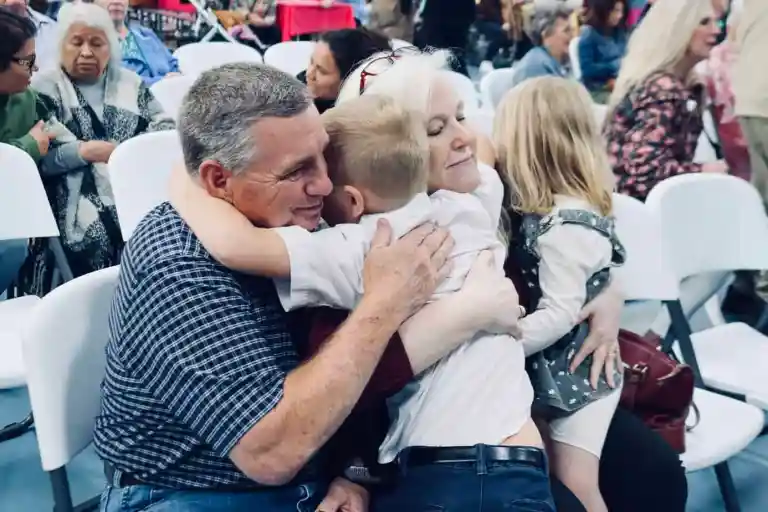 Grandparents embracing two young children at a school event