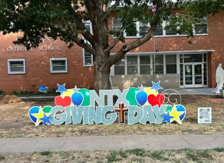 NTX Giving Day sign displayed in front of the Catholic school building