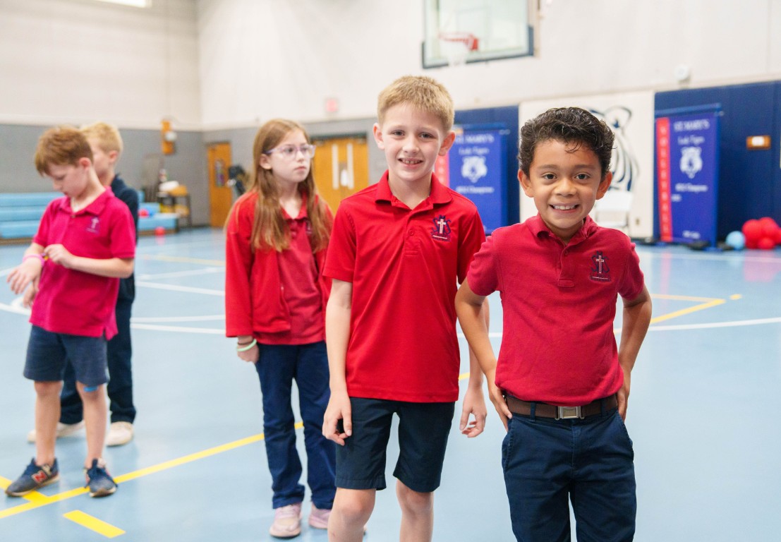 Students in red uniforms participating in physical education class gymnasium