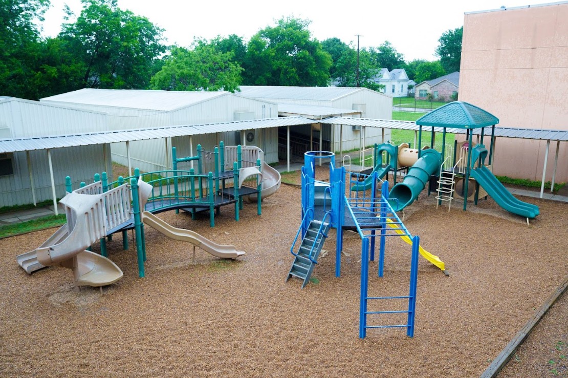 Outdoor school playground with slides and climbing structures on mulch