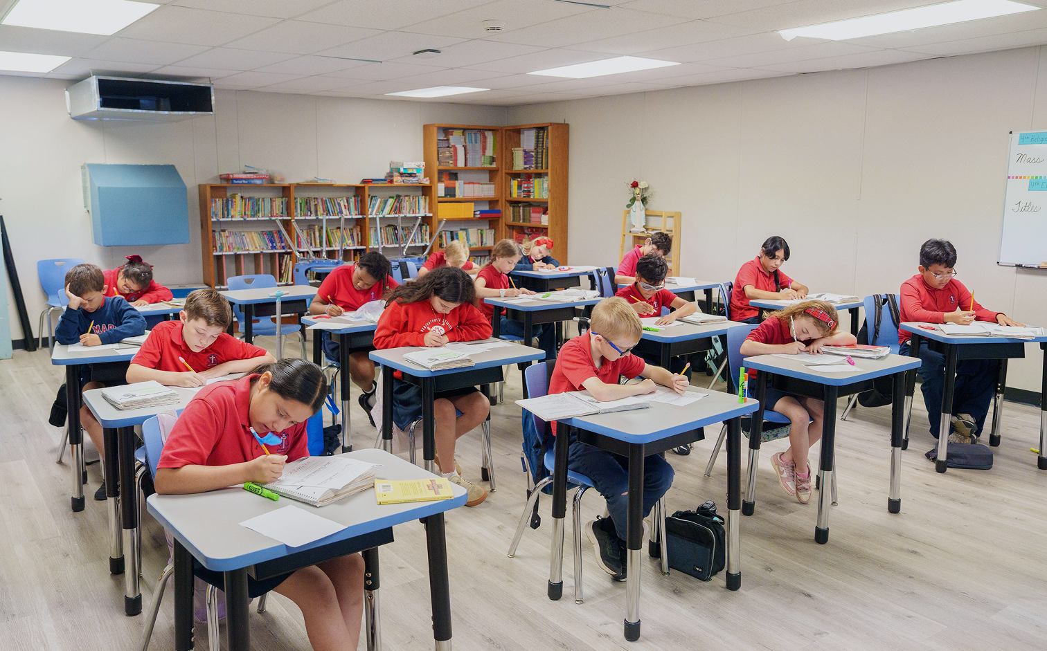 Students in red uniforms writing at desks in a classroom