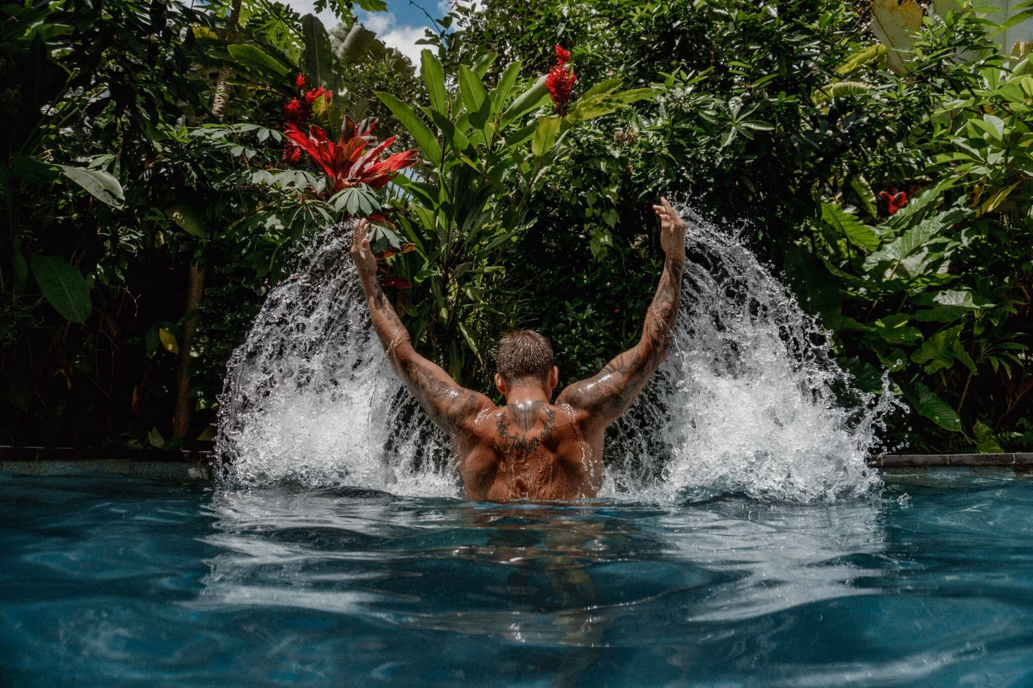 Tattooed man splashes water in a swimming pool