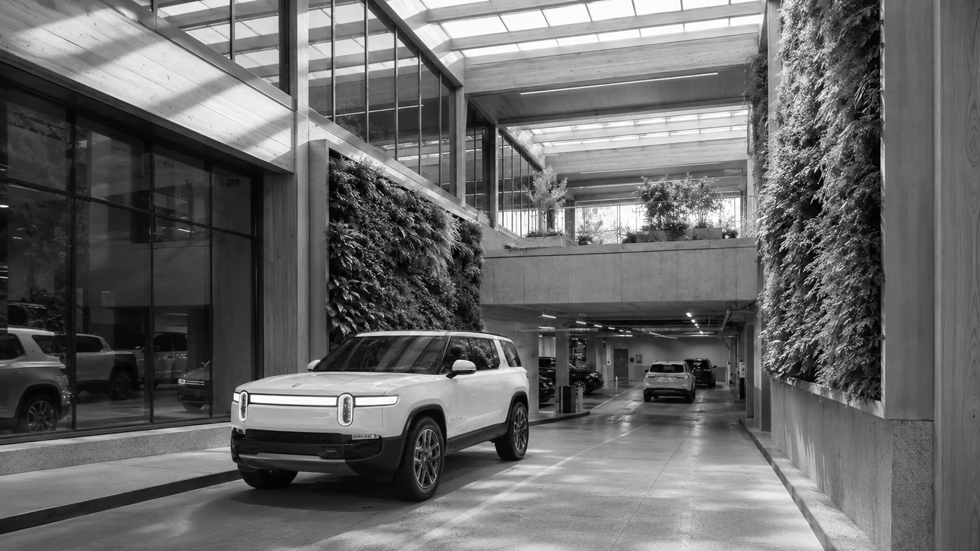 Modern white SUV parked indoors near walls covered with vertical gardens and glass windows.