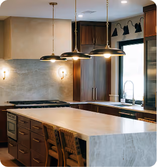 Modern kitchen with marble island, wooden cabinets, pendant lights, and large window by the sink.