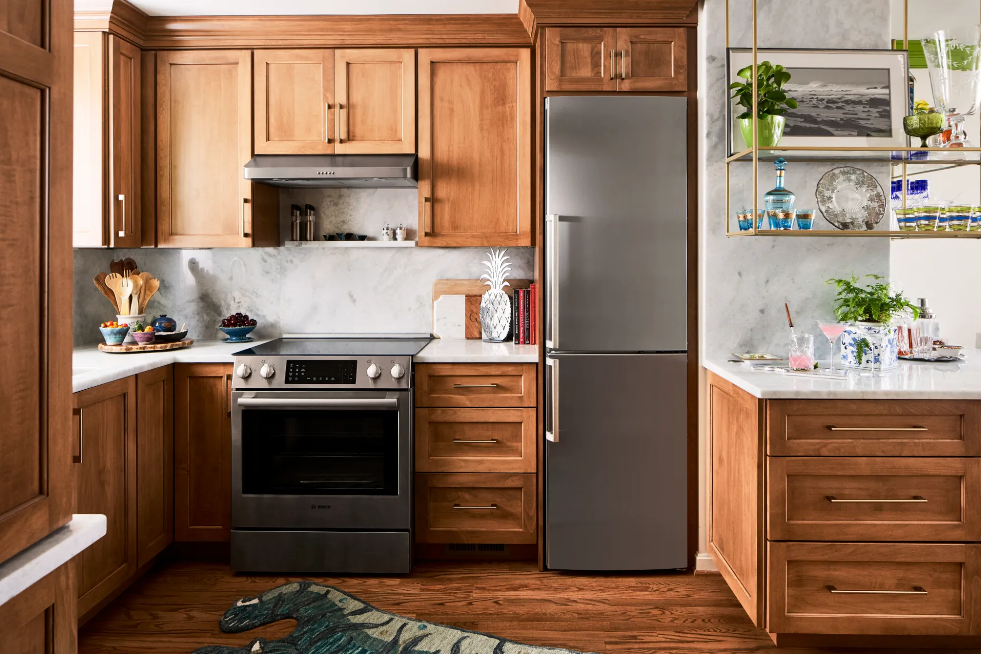 Kitchen with wooden cabinets, stainless steel oven and fridge, white countertops, and decorative plants.