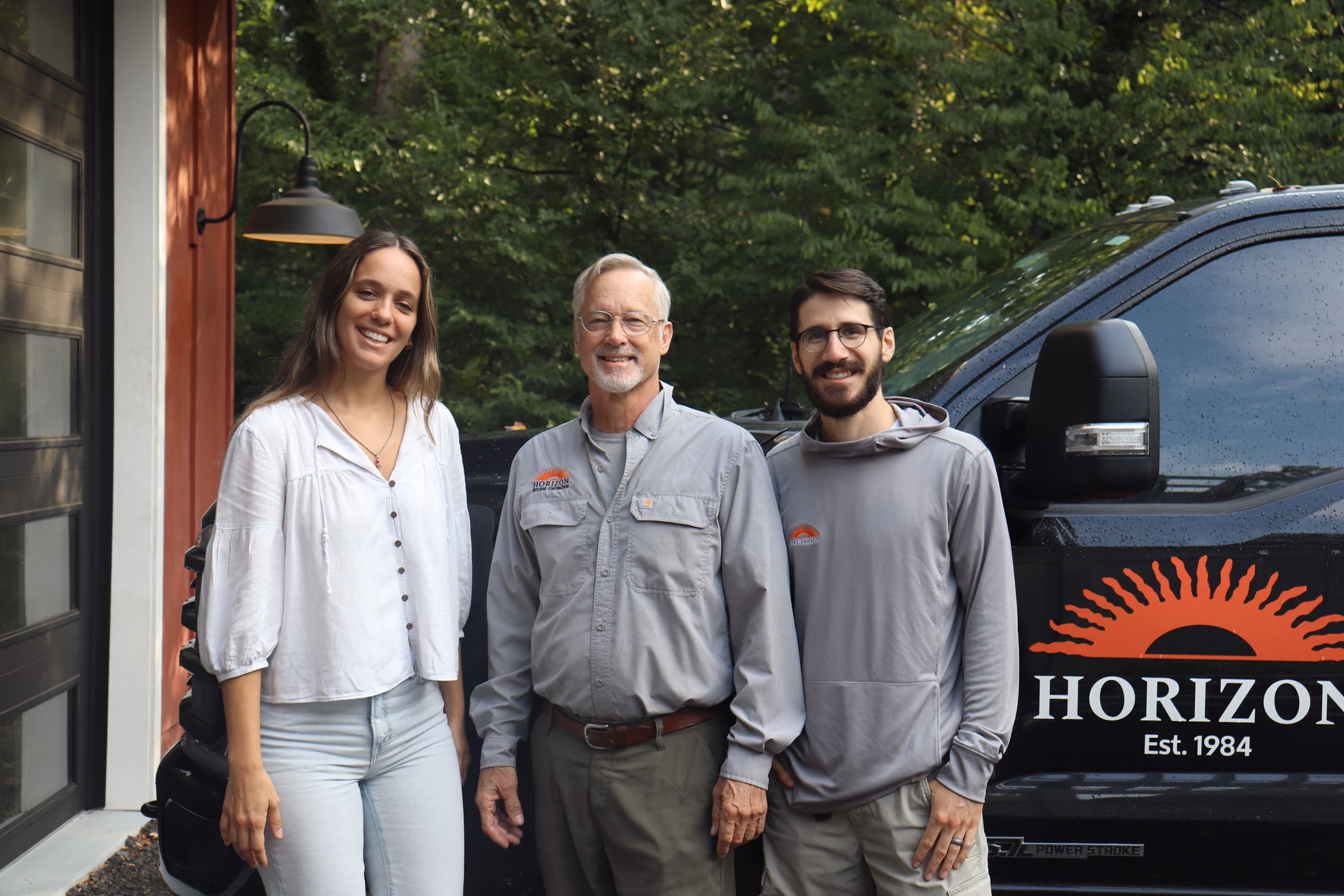 Three people smiling in front of a black truck with Horizon logo and Est. 1984 text.