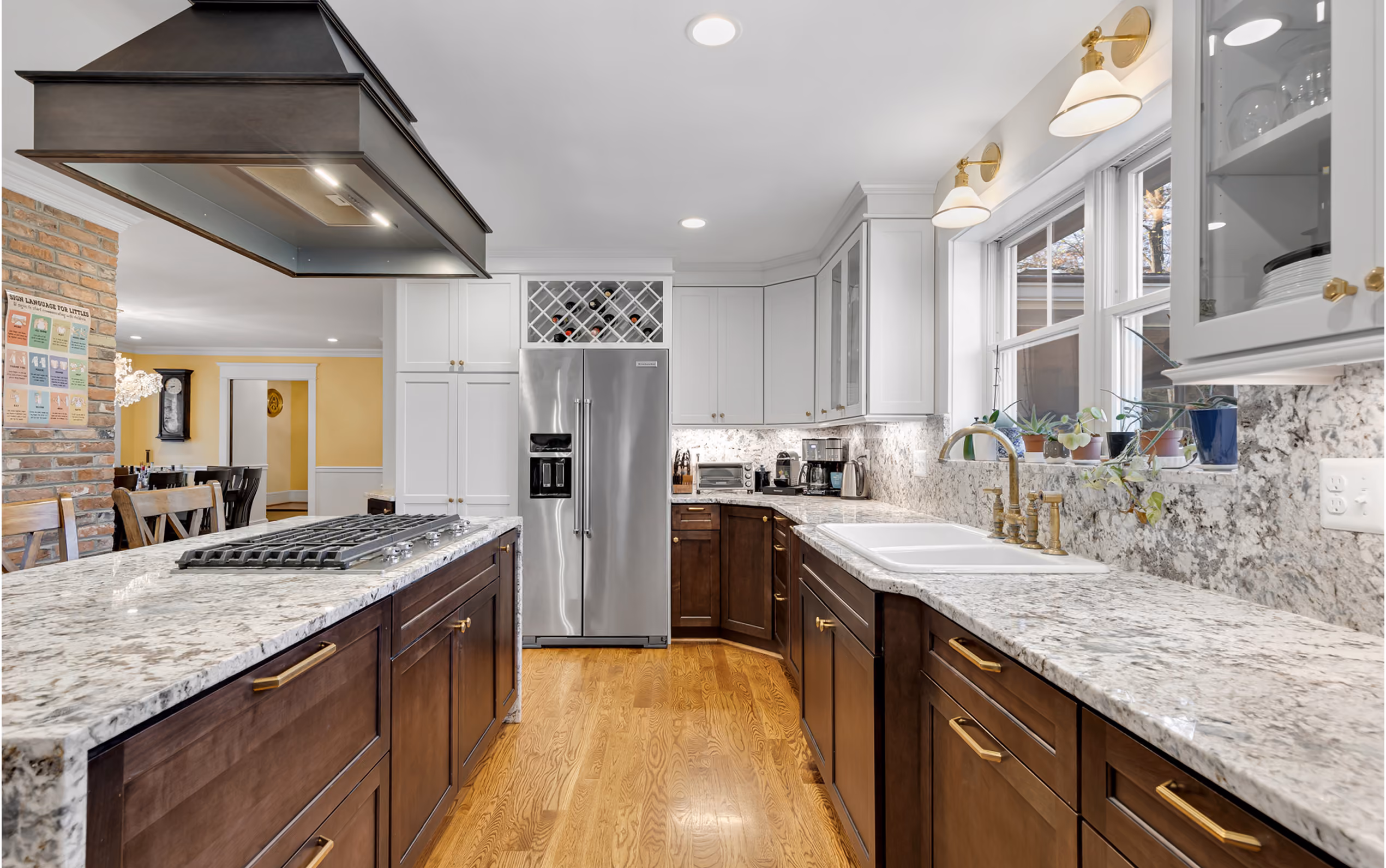 Modern kitchen with granite countertops, dark wood lower cabinets, white upper cabinets, and stainless steel refrigerator.