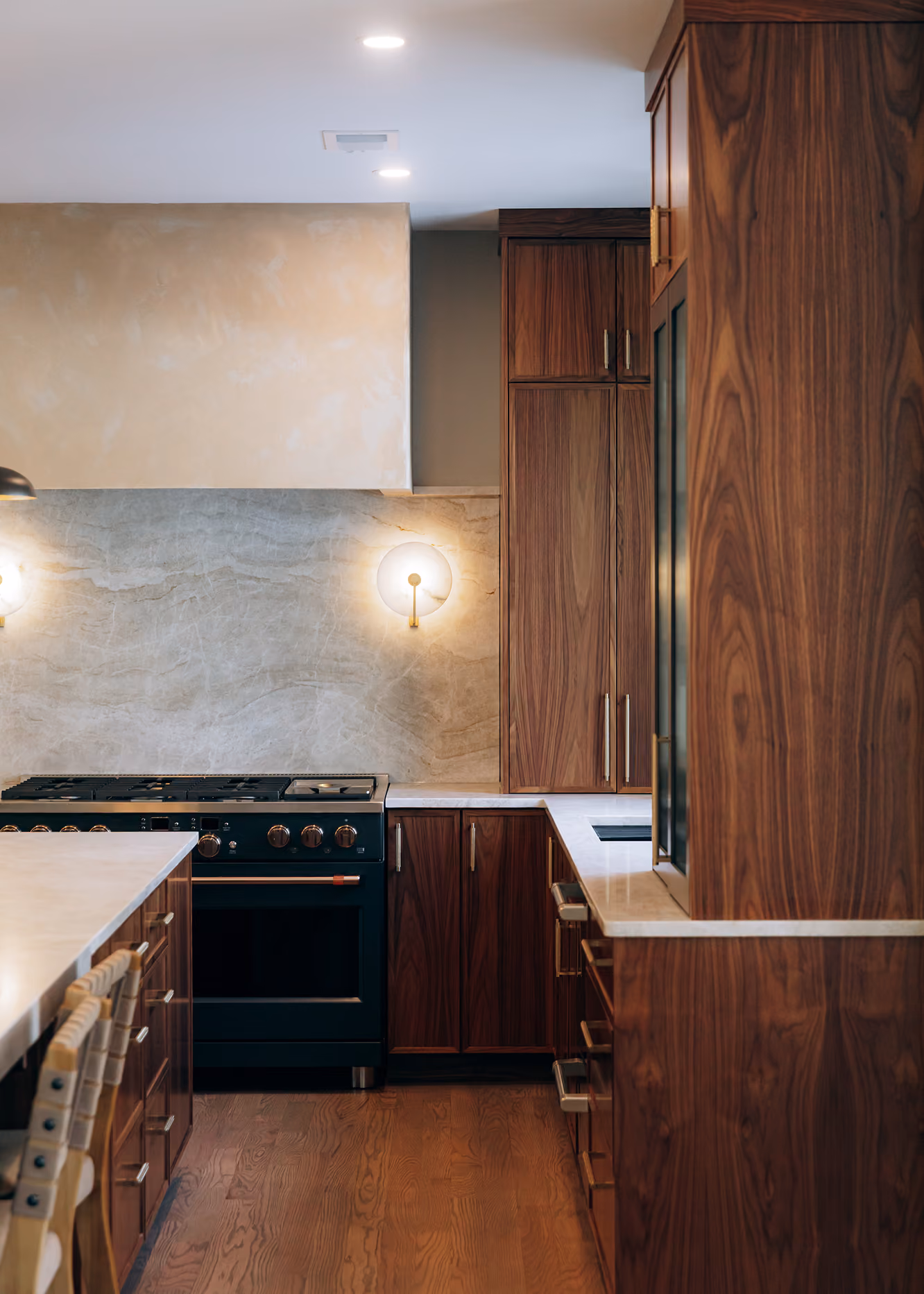 Modern kitchen with wooden cabinets, dark stove, marble countertops, and wooden floor.