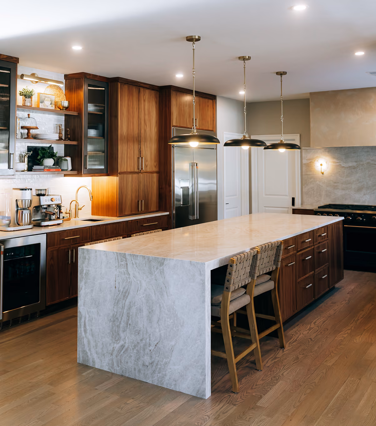 Modern kitchen with a large marble island, wooden cabinets, stainless steel appliances, and pendant lights.