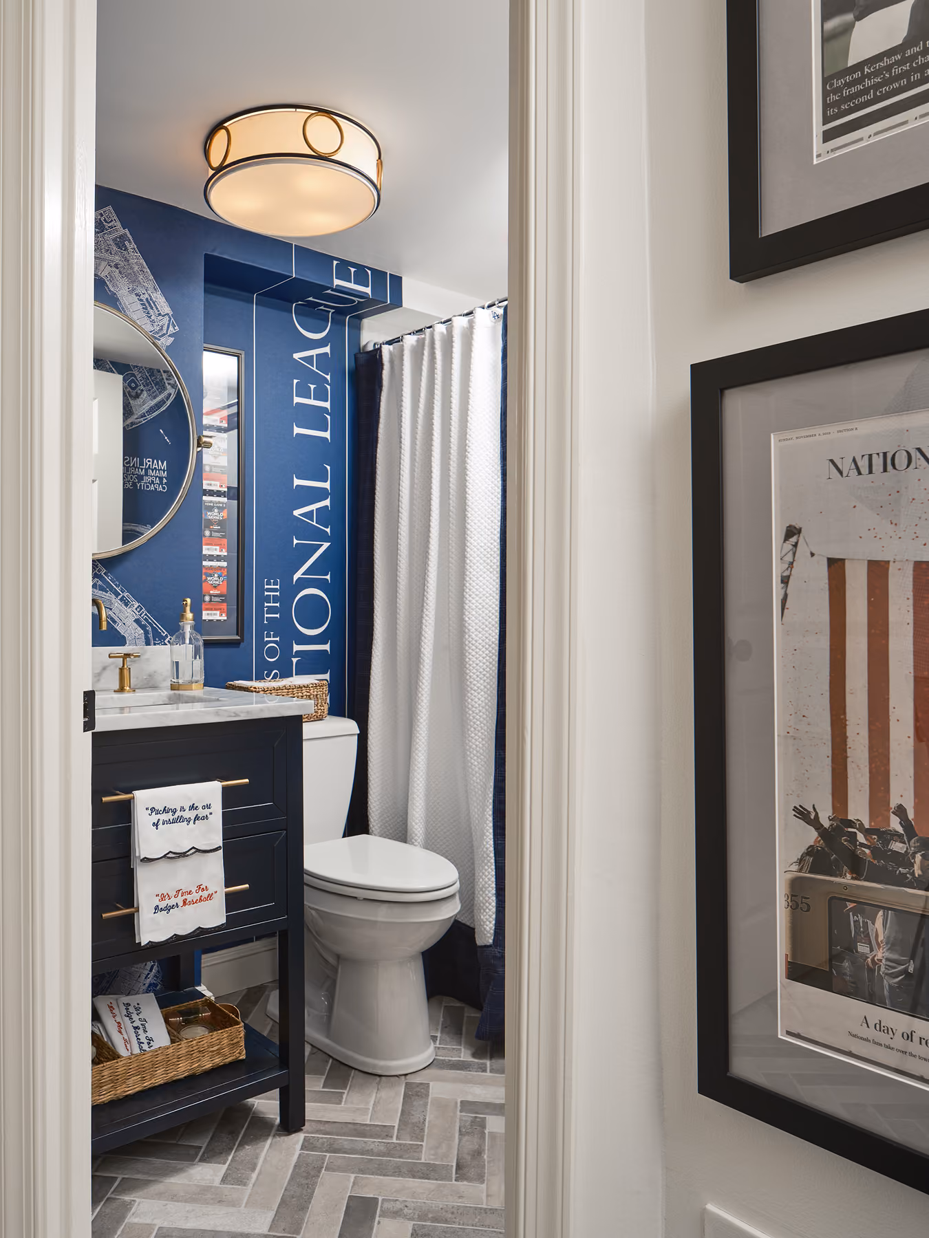 Small bathroom with navy blue vanity, white toilet, shower with white curtain, and navy accent wall text.