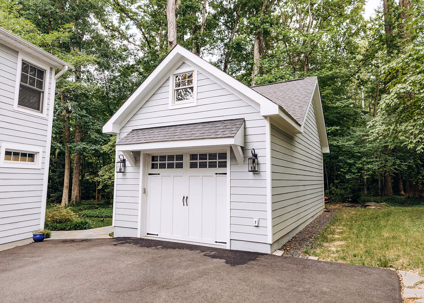 White detached garage with carriage-style doors and a gable window, built beside the main house