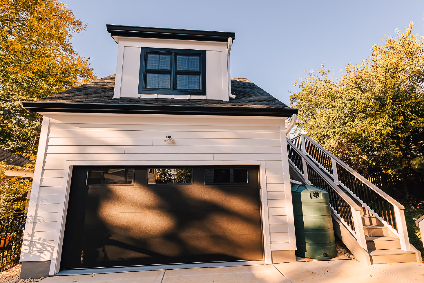 White garage with an upper-level apartment, dormer window and exterior stair entrance