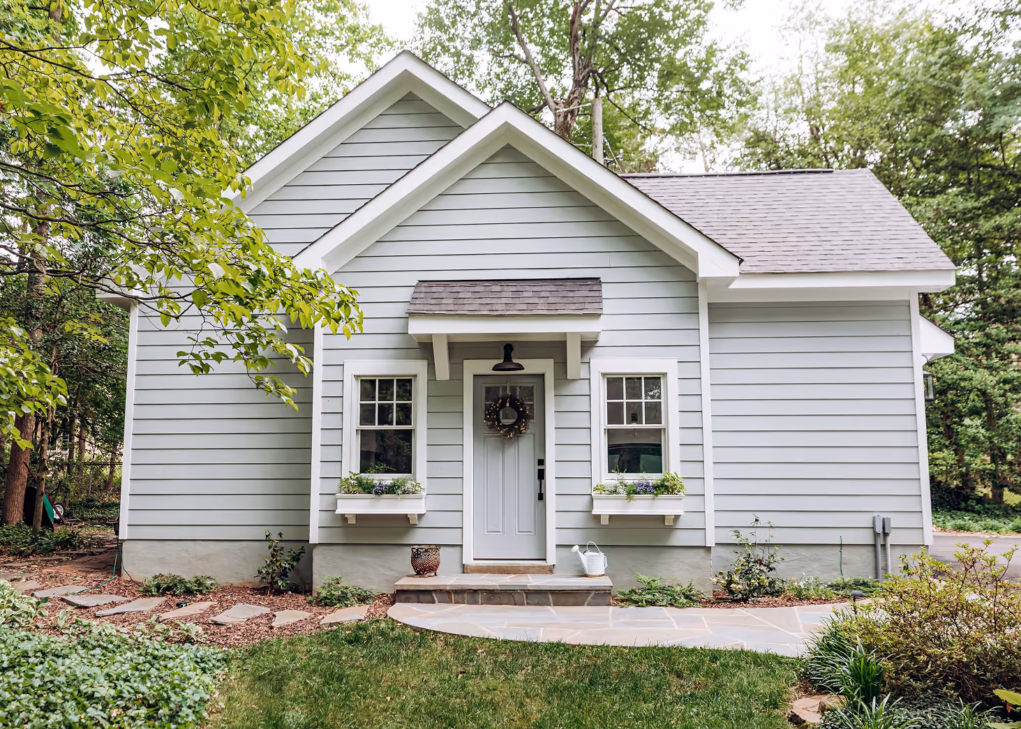 Gray cottage-style detached ADU with a covered front entry and window boxes