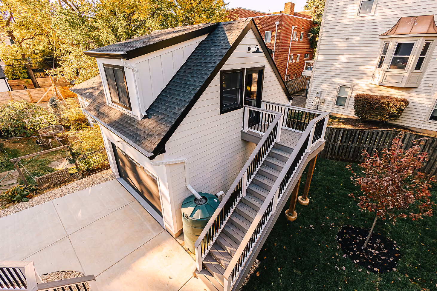Aerial view of a white backyard ADU with exterior stairs leading to a second-floor entrance