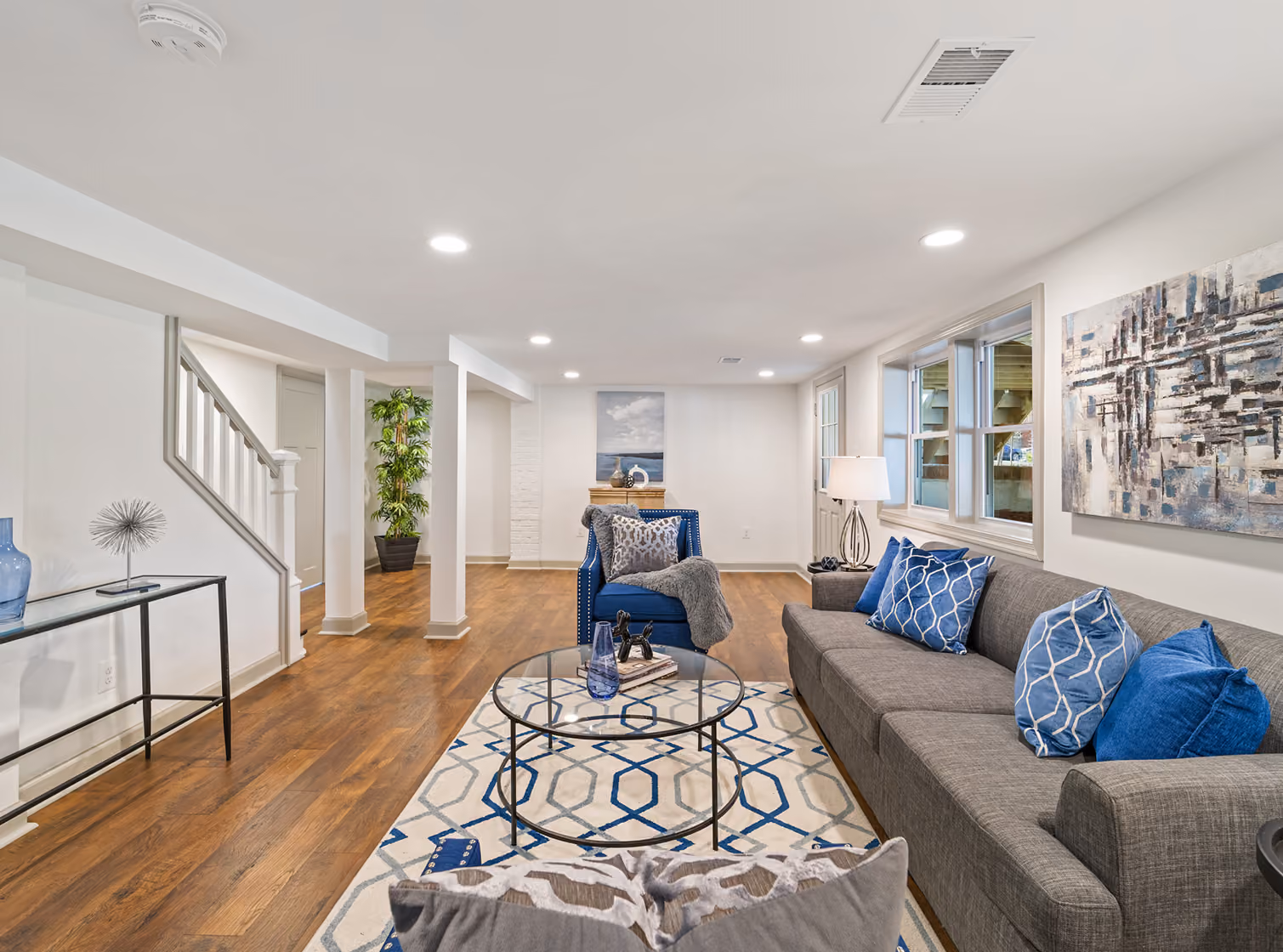 Bright finished basement family room with a gray sectional, hardwood floors and recessed lighting