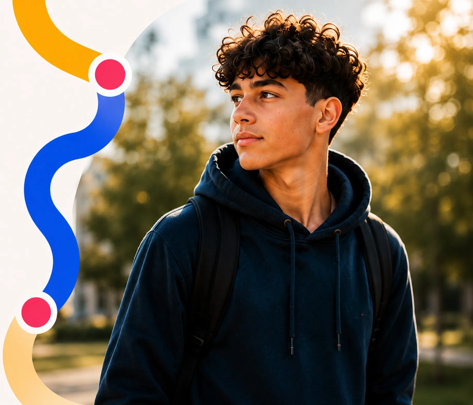 Young man with curly hair wearing a dark hoodie and backpack looking to the side outdoors.