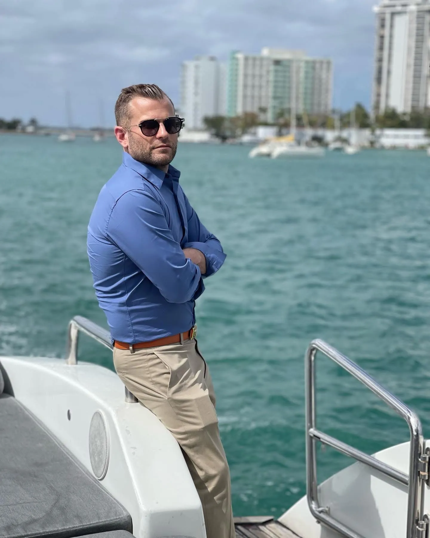 Justin Keeperman wearing sunglasses aboard a boat on a city waterfront