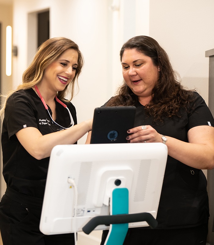 Dr. Ashley Civetti reviewing treatment information on a tablet with a patient at Pearl Palm Beach Dental in Royal Palm Beach FL