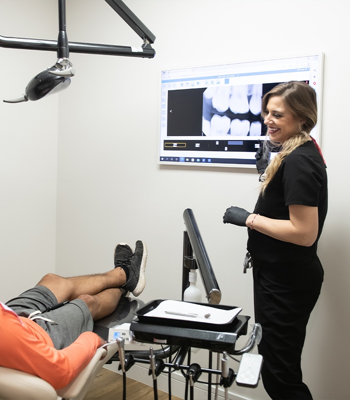 Dentist reviewing dental X-rays on a monitor with a patient in the treatment chair at Pearl Palm Beach Dental in Royal Palm Beach FL