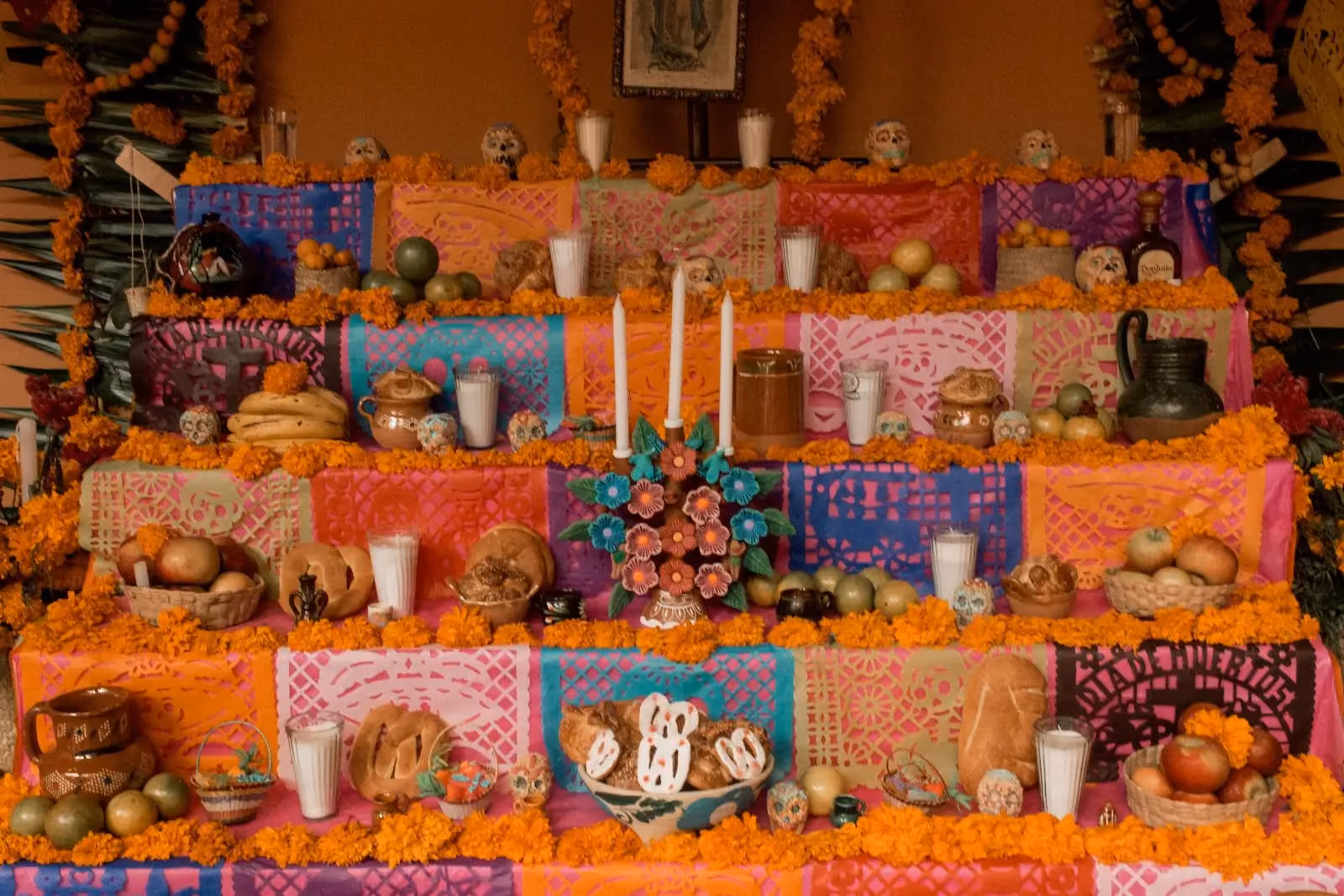 A Dia de Muertos ofrenda altar set with marigolds, candles, food and framed photographs of the dead