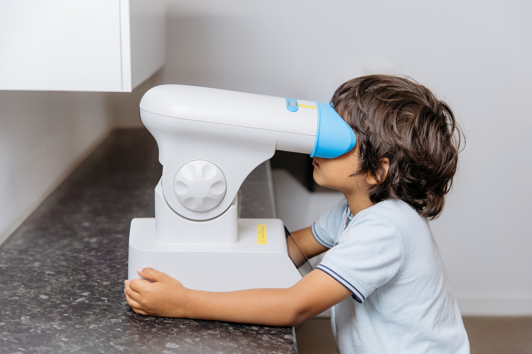 Child looking into a tabletop repeated low-level red-light therapy device