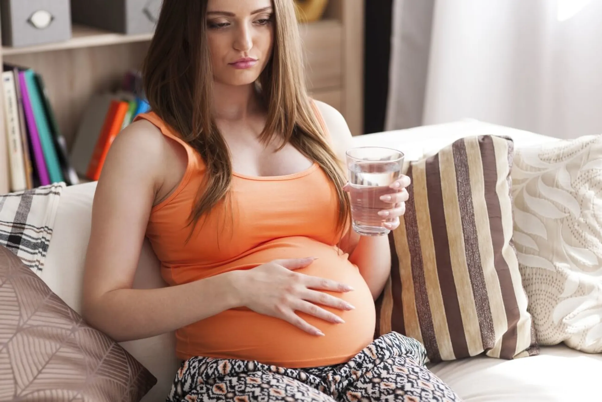 femeie însărcinată stând pe canapea | durere abdominală în sarcină