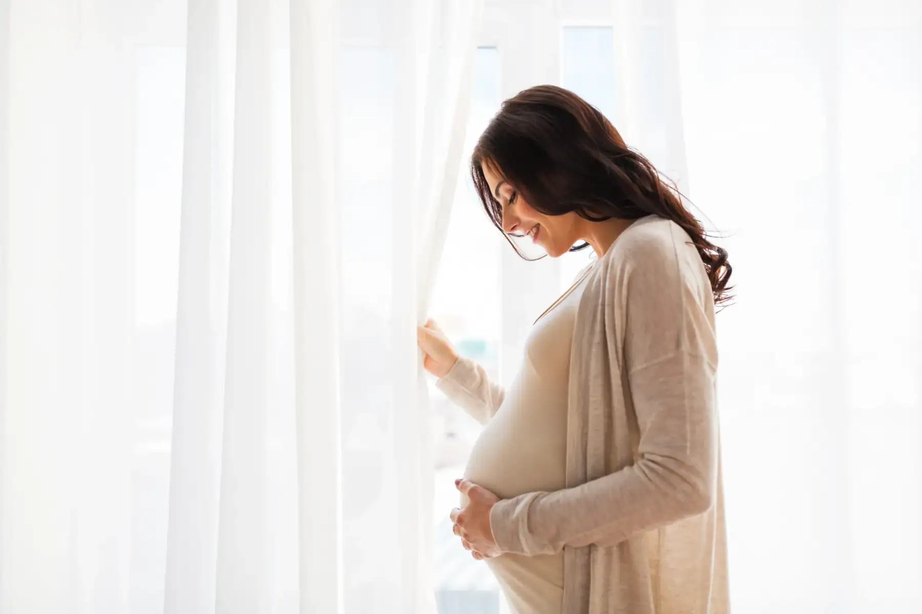 o gravidă stă lângă fereastră | teste prenatale în al treilea trimestru