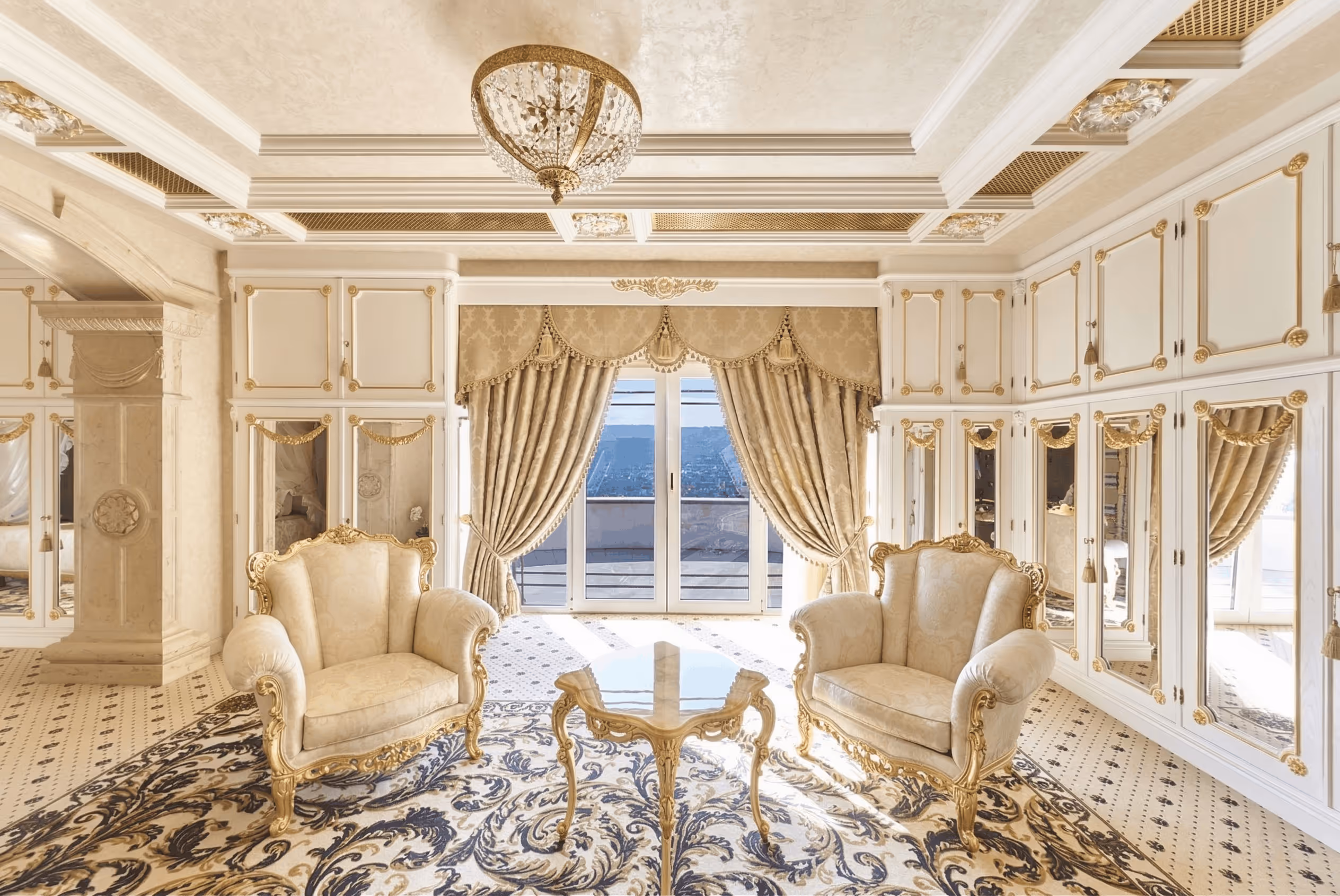 Elegant living room with two ornate armchairs, patterned rug, gold-accented furniture, and large window draped with curtains.