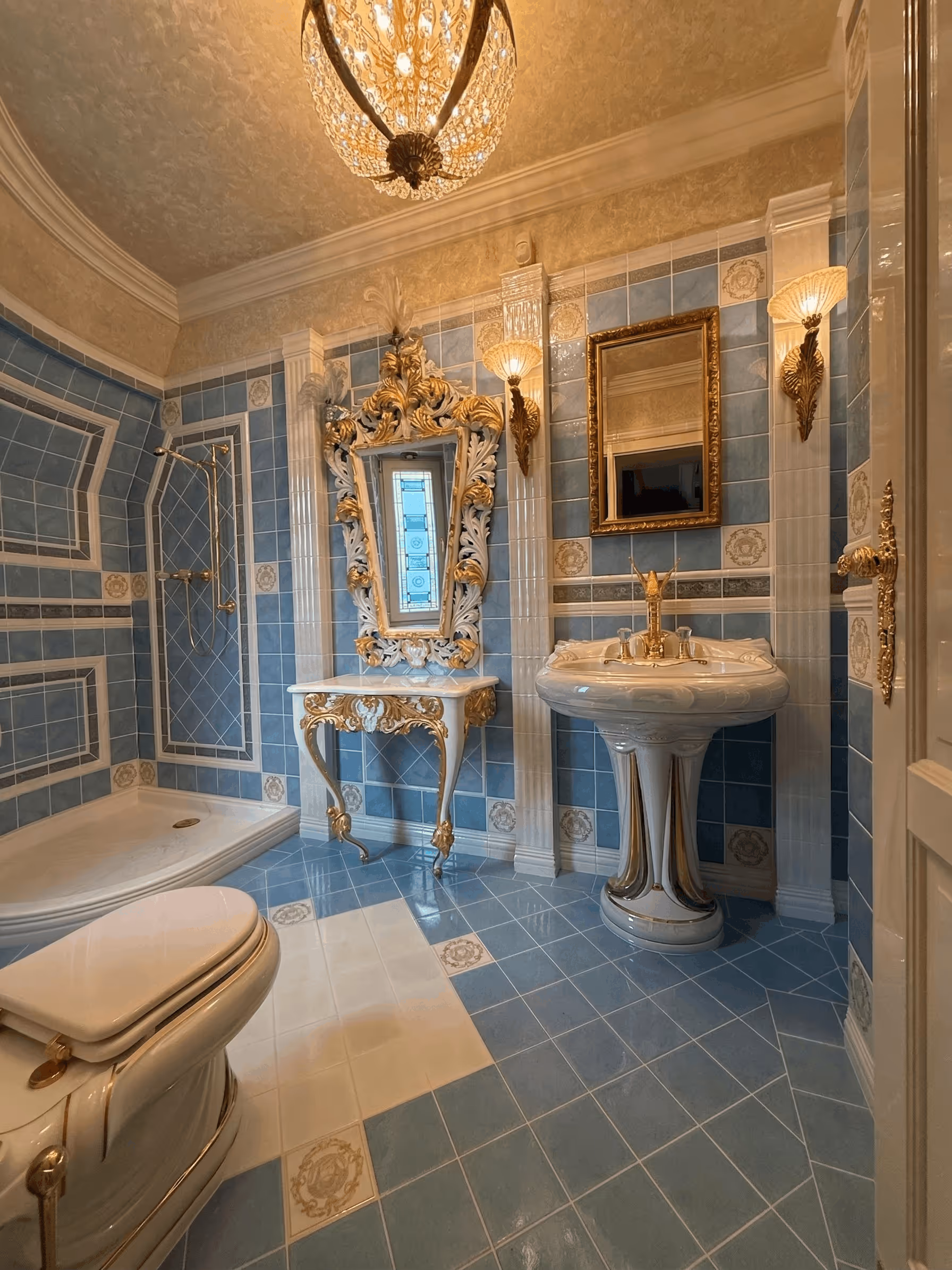 Luxurious bathroom with blue tiled walls and floors, ornate gold-accented mirror, sink, and fixtures.