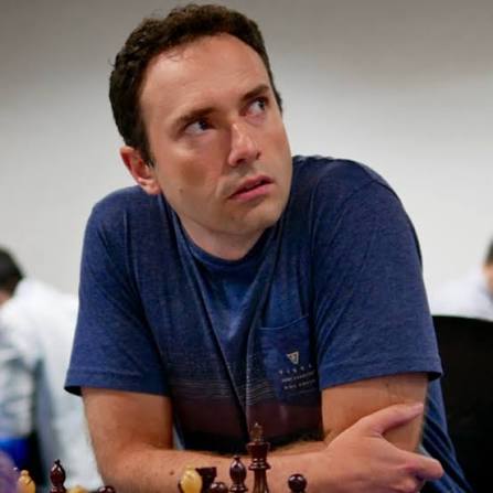 Portrait of Eugene Perelshteyn sitting in front of a chess board, staring off into the distance.