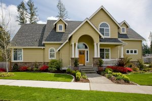 The exterior od a suburban home with a well-kept front yard, porch, and curve-top windows