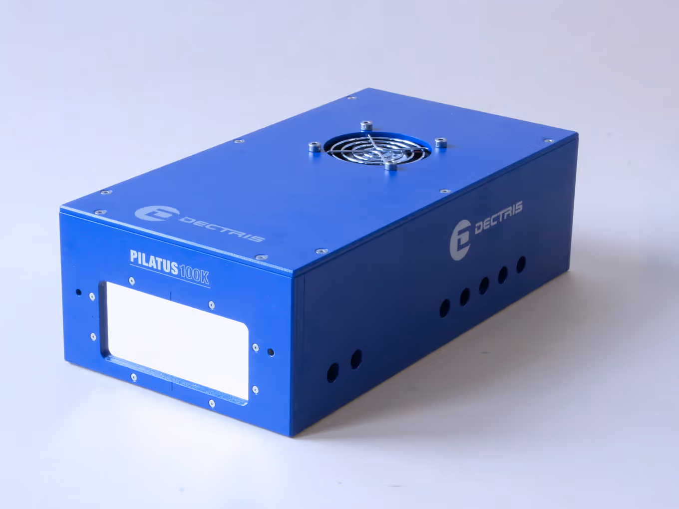 Blue rectangular electronic device labeled PILATUS 100K and Dectris with ventilation holes and a cooling fan on top.