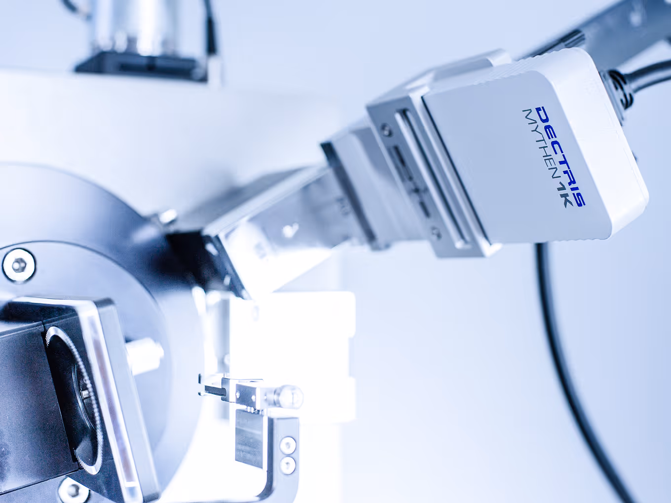 Close-up of a Decatris MYTHEN 1K scientific instrument with a metallic component and connected cable.