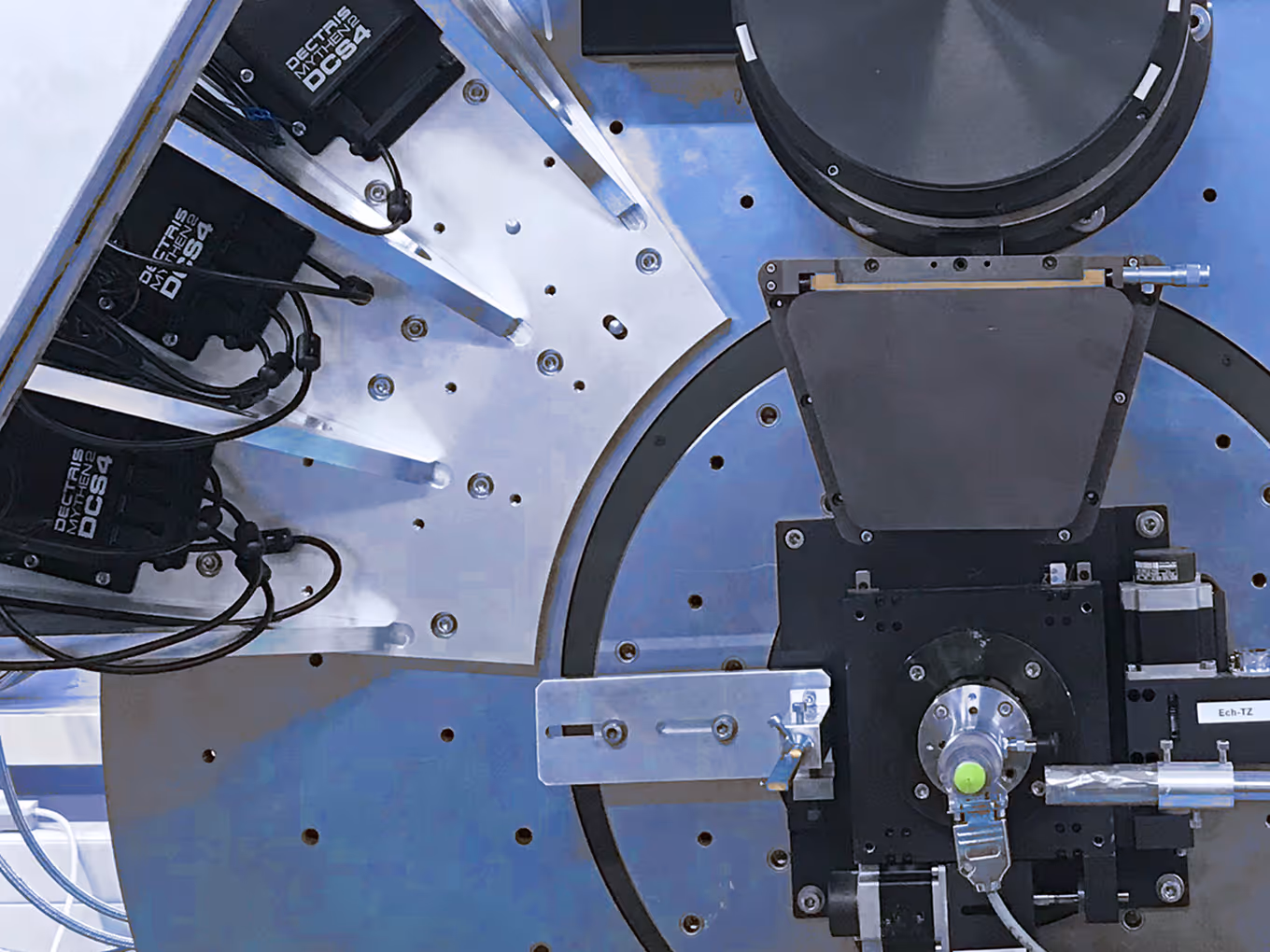 Close-up of scientific instrument components with detectors labeled Dectris Mythen DC54 and mechanical mounts.