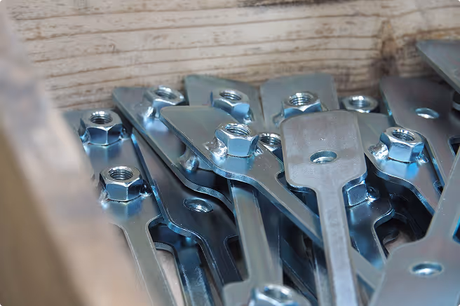 Close-up of shiny metal wrench heads with attached nuts stacked in a wooden crate.