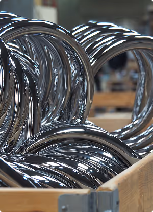 Close-up of shiny metal coils stacked inside a wooden crate.