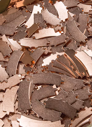 Close-up of numerous shiny copper-colored curved metal pieces scattered closely together.