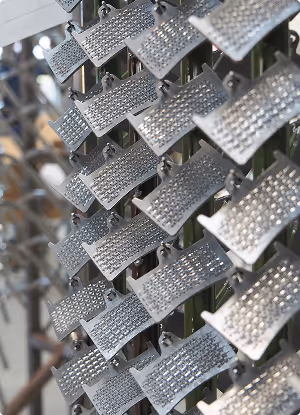 Rows of shiny silver metallic tags with a textured, studded surface hanging on hooks.
