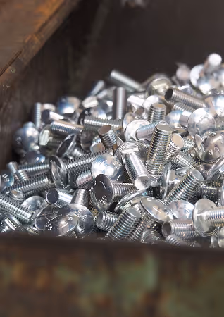 Close-up of a pile of shiny metal screws in a container.