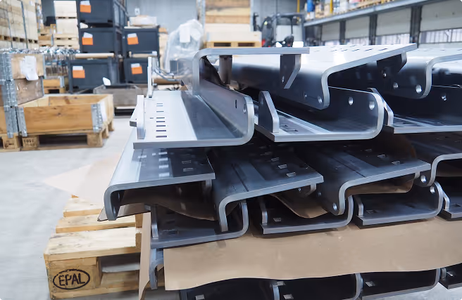 Stack of curved metal profiles stored on a wooden pallet in a warehouse.
