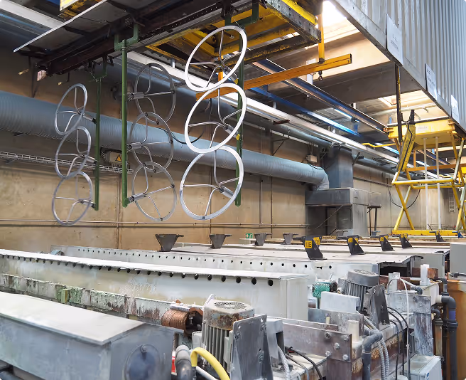 Metal rings hanging from a ceiling in an industrial factory environment with machinery below.