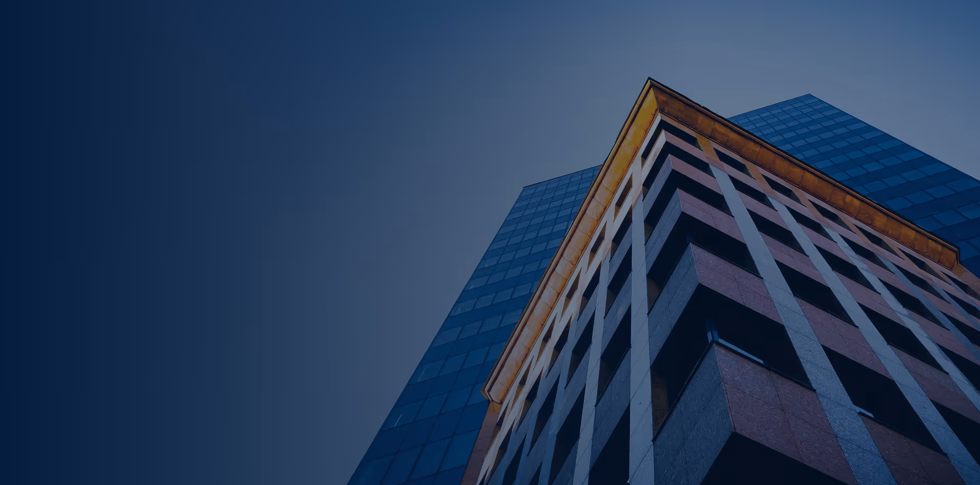 Low-angle view of modern high-rise buildings with glass and concrete facades against a blue sky.