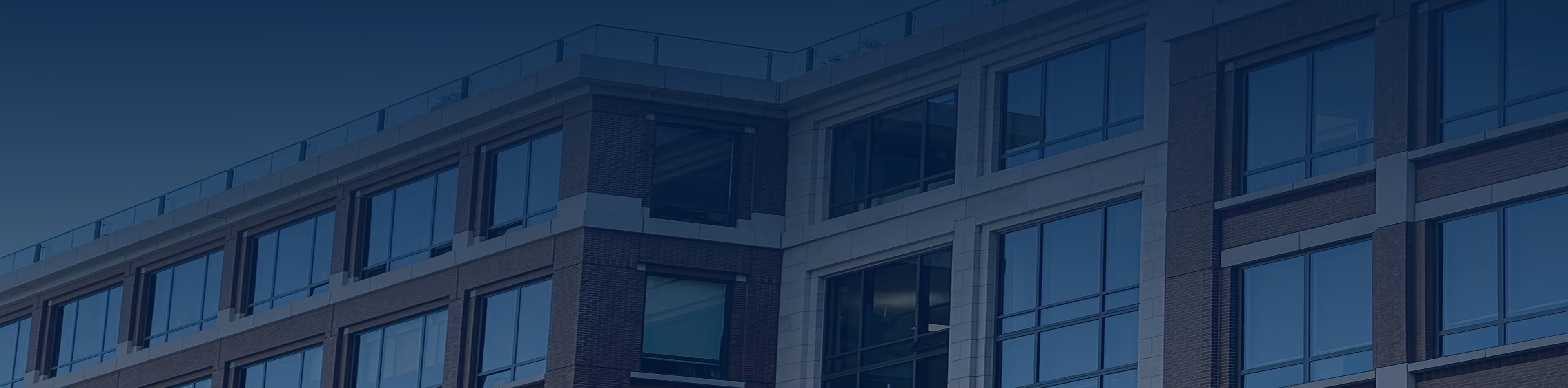 Modern office building with large reflective glass windows and brick exterior.
