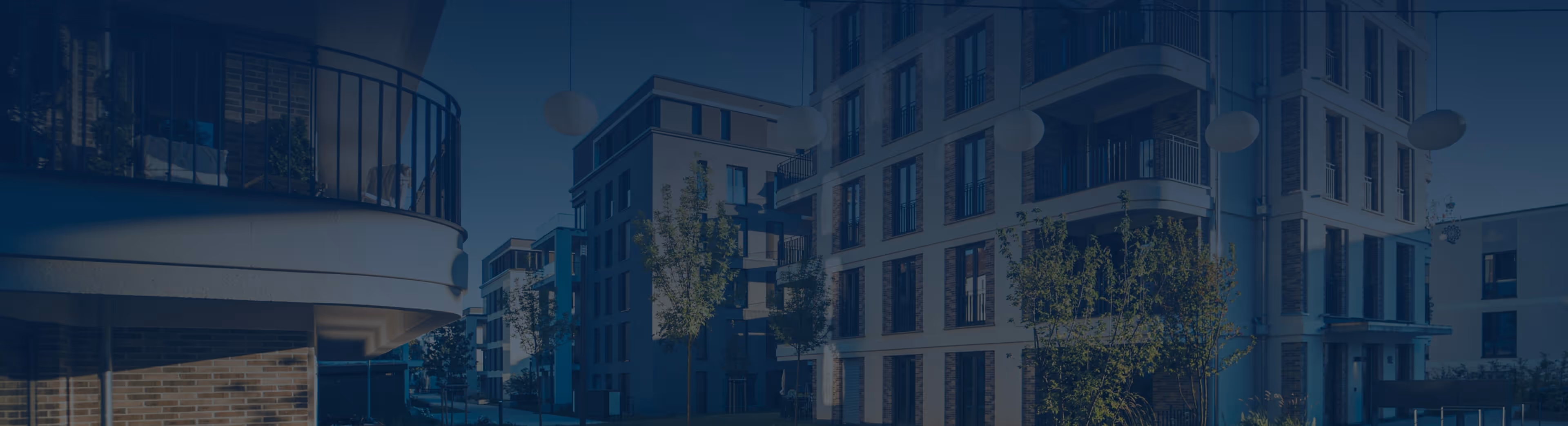 Modern apartment buildings with balconies and greenery under clear blue sky.