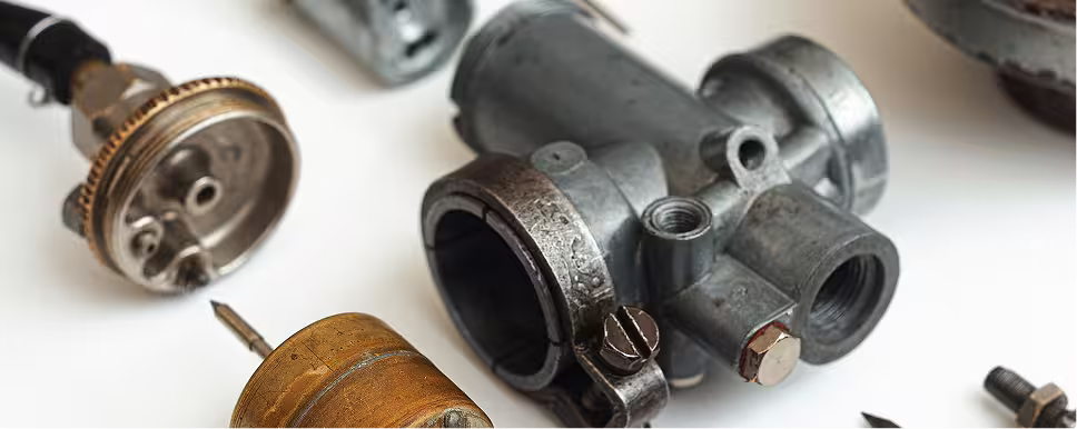 Close-up of various old metal mechanical parts and screws on a white surface.