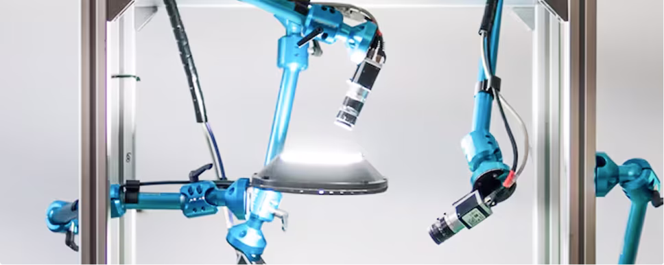 Blue multi-jointed robotic arms with cameras inside a glass enclosure.