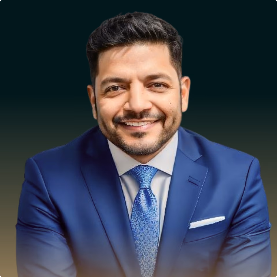 Smiling man with black hair and beard wearing a blue suit, white shirt, and patterned blue tie.
