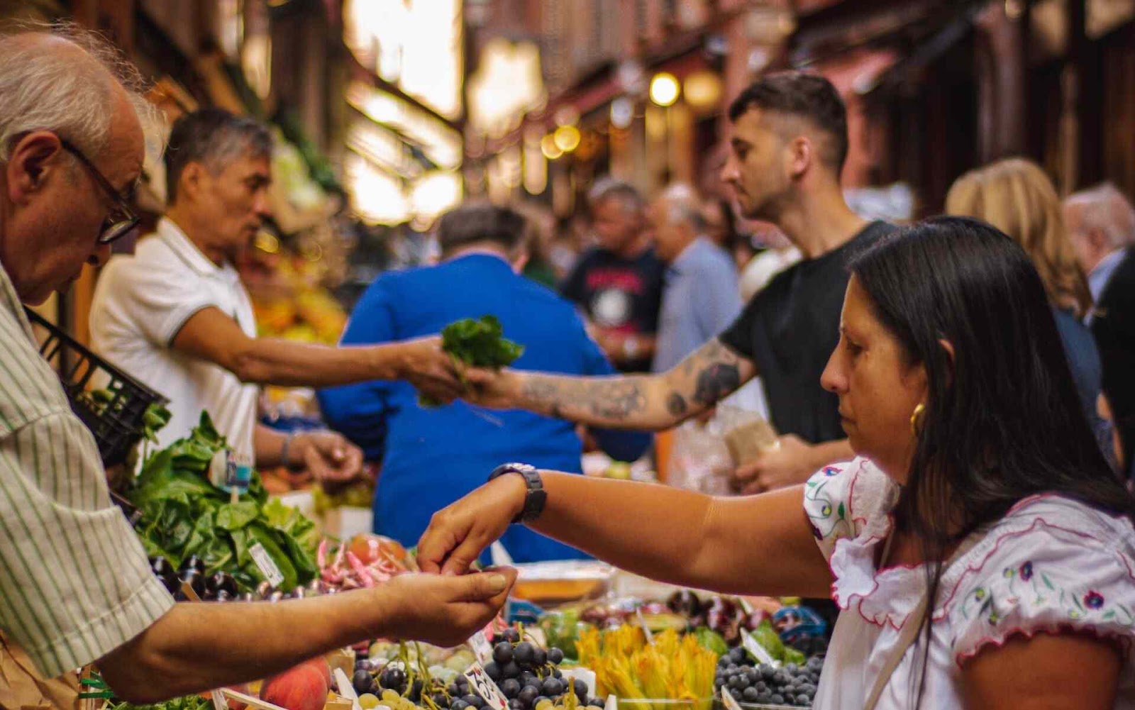 Busy street market with numerous vendors selling from booths to a crowd of buyers.