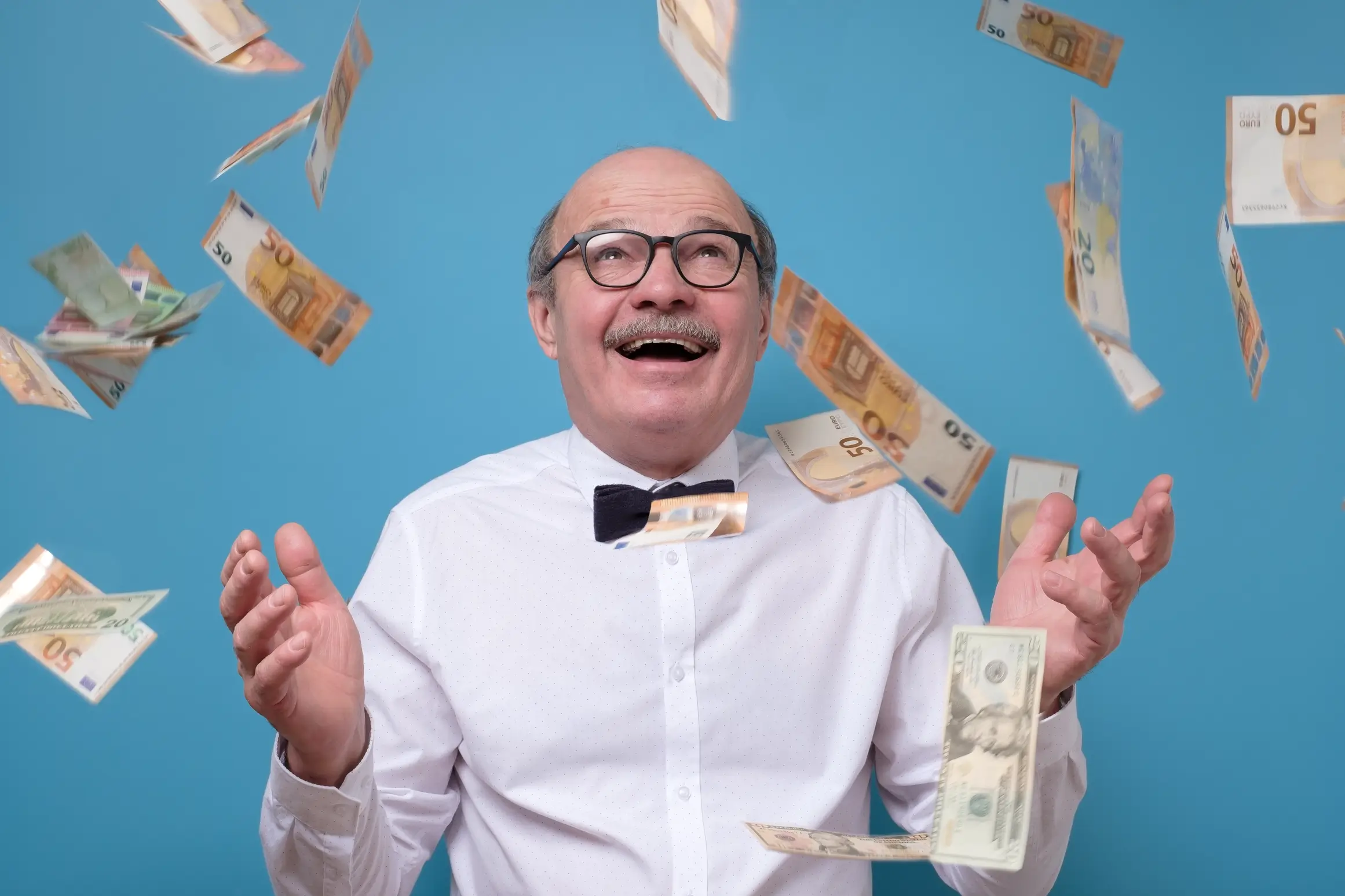 An older gentleman in glasses with money falling on him to represent value creation in procurement