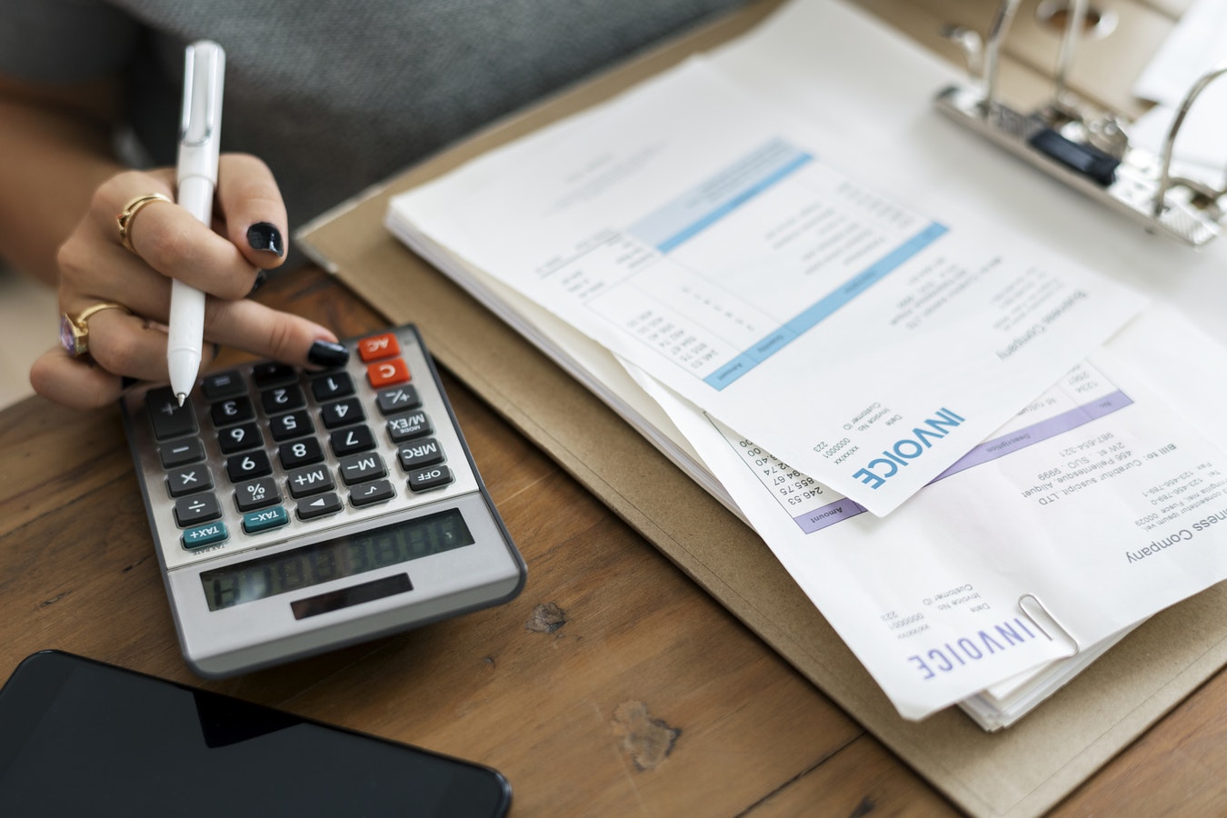 A woman trying to manage procurement flow for her business with a calculator and purchasing documents